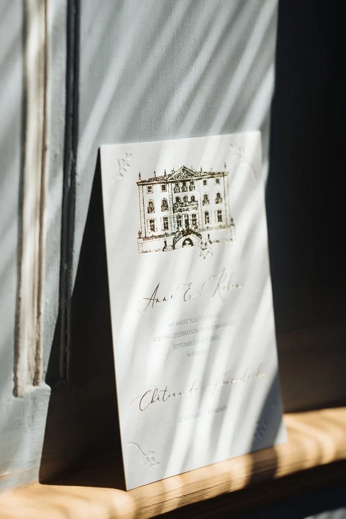 Fein geprägte Hochzeitseinladung mit Illustration des Chateau de Fonscolombe in Frankreich, kombiniert mit Goldfolienprägung und klassischem französischem Design